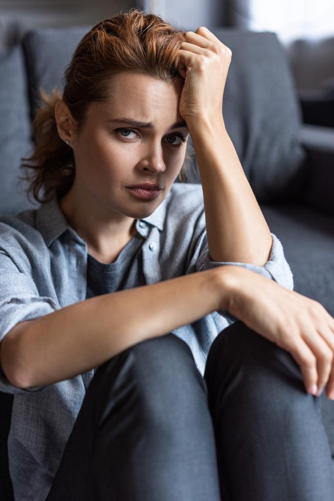 selective focus of upset woman looking at camera while sitting at home - Photo, Image