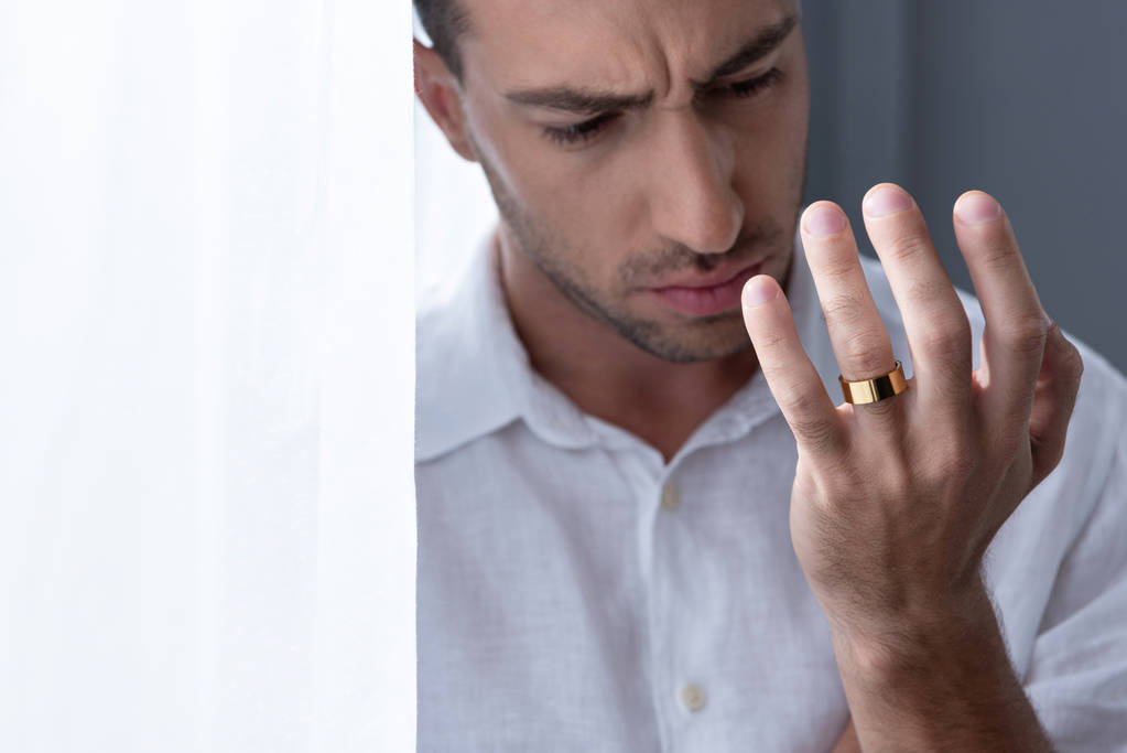 κατάθλιψη άντρας με λευκό πουκάμισο κοιτάζοντας το δαχτυλίδι στο δάχτυλο - Φωτογραφία, εικόνα
