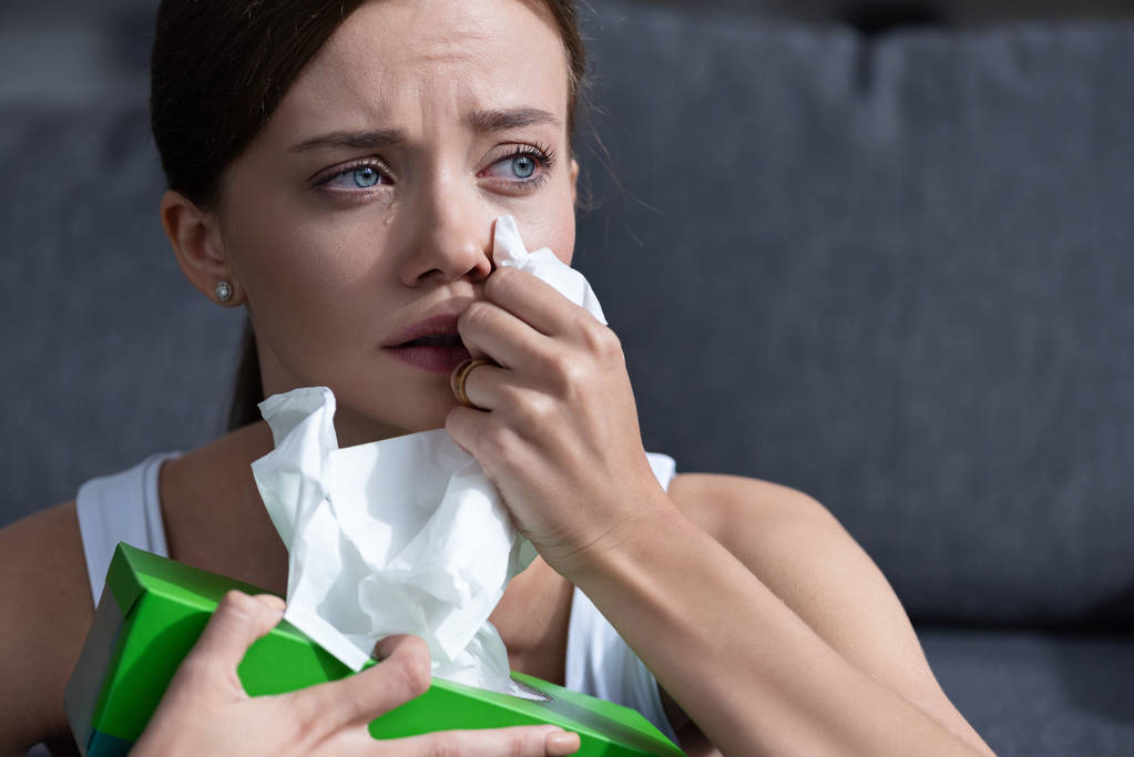 засмучена молода жінка плаче і витирає сльози вдома
 - Фото, зображення