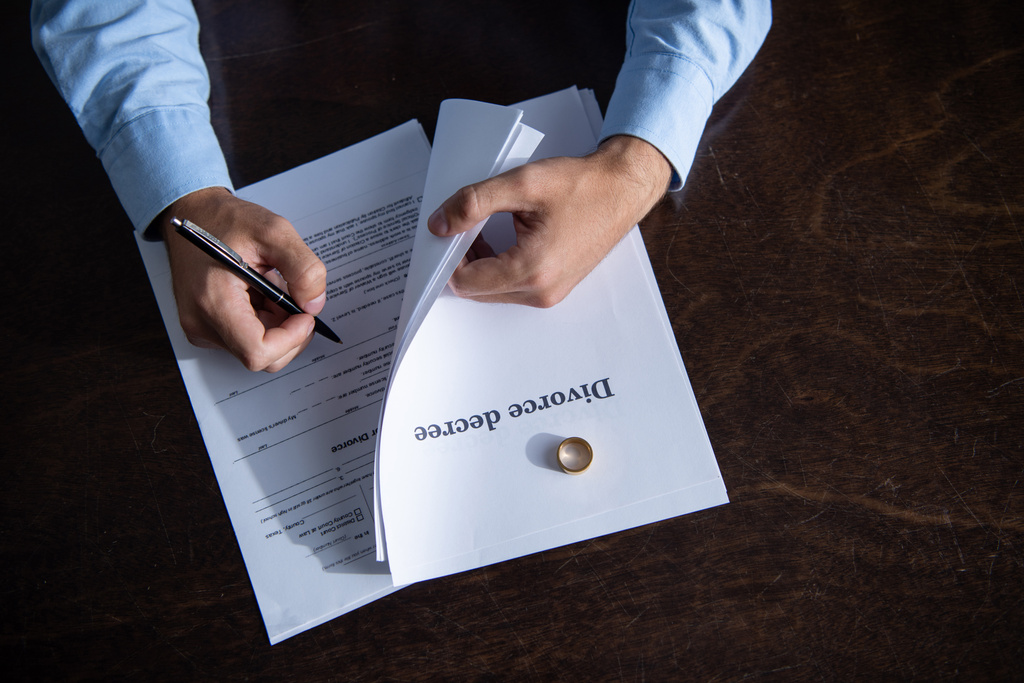 vista parcial del hombre sentado en la mesa y firmando documentos de divorcio
 - Foto, imagen