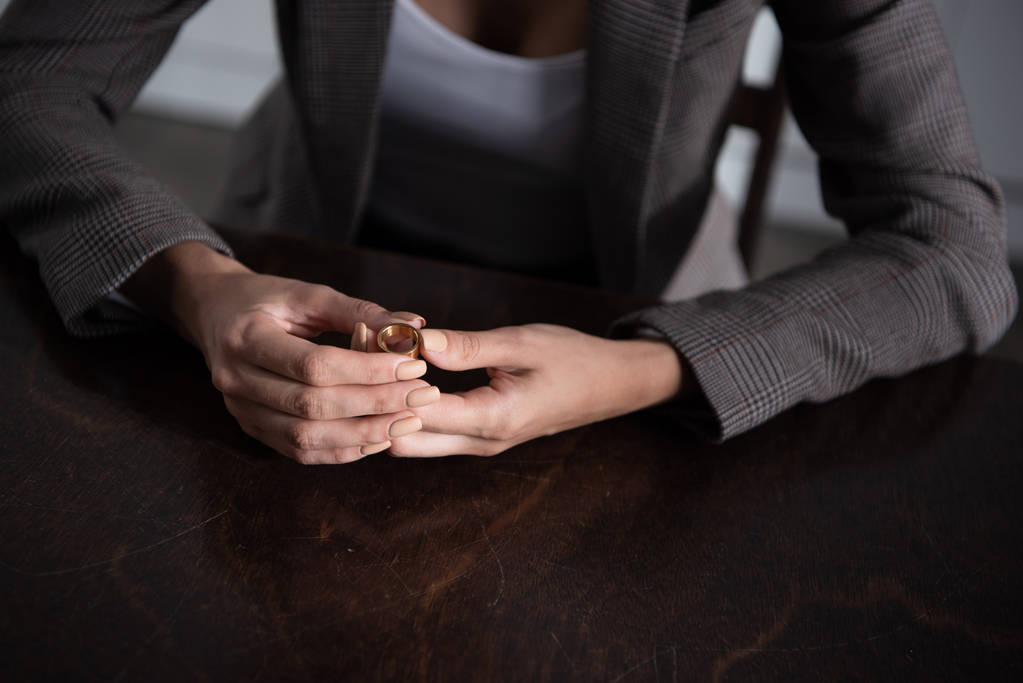 vue partielle de la femme en veste assise à la table et tenant l'anneau à la maison
 - Photo, image
