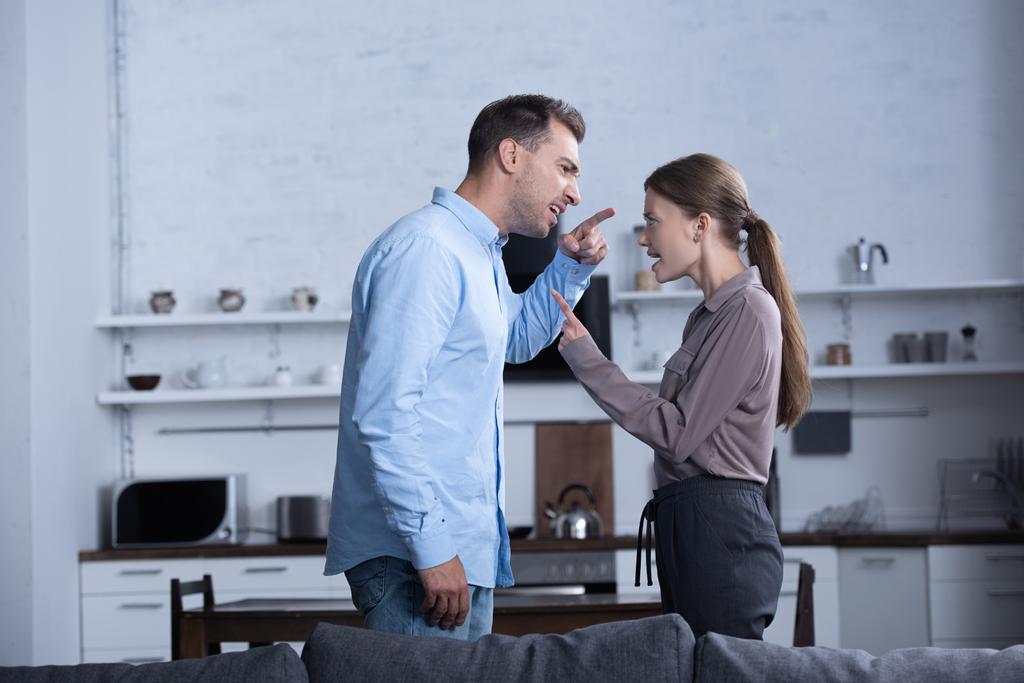 side view of angry husband and wife pointing with fingers and screaming at each other - Photo, Image