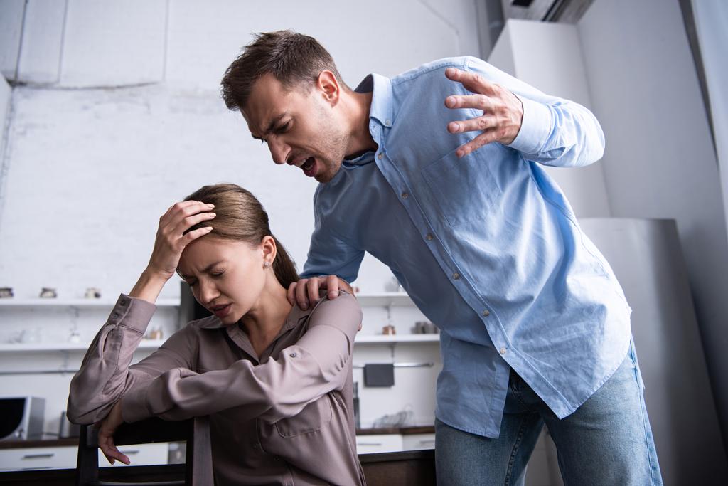 agresivo hombre en camisa gritando a asustado esposa en casa
 - Foto, Imagen