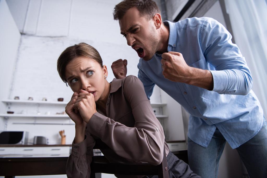 aggressiivinen mies pitää nyrkit pystyssä ja huutaa peloissaan vaimo
 - Valokuva, kuva