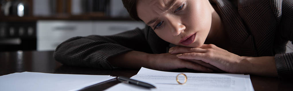πανοραμική βολή θλιμμένη γυναίκα στο τραπέζι με δαχτυλίδι και έγγραφα - Φωτογραφία, εικόνα