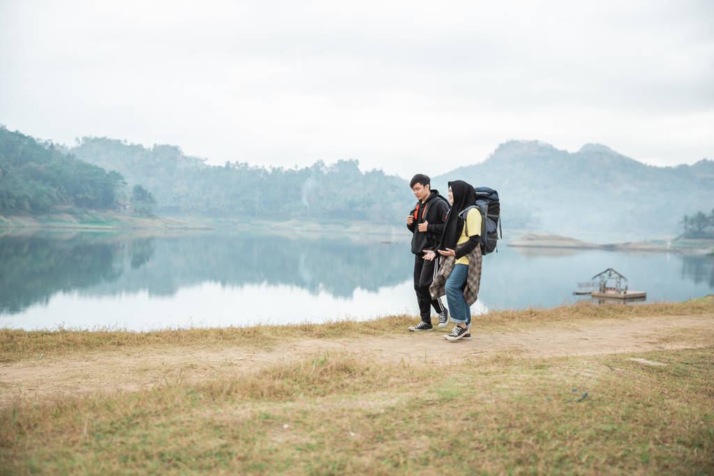 pareja de excursionistas con mochilas caminando lado del lago
 - Foto, imagen