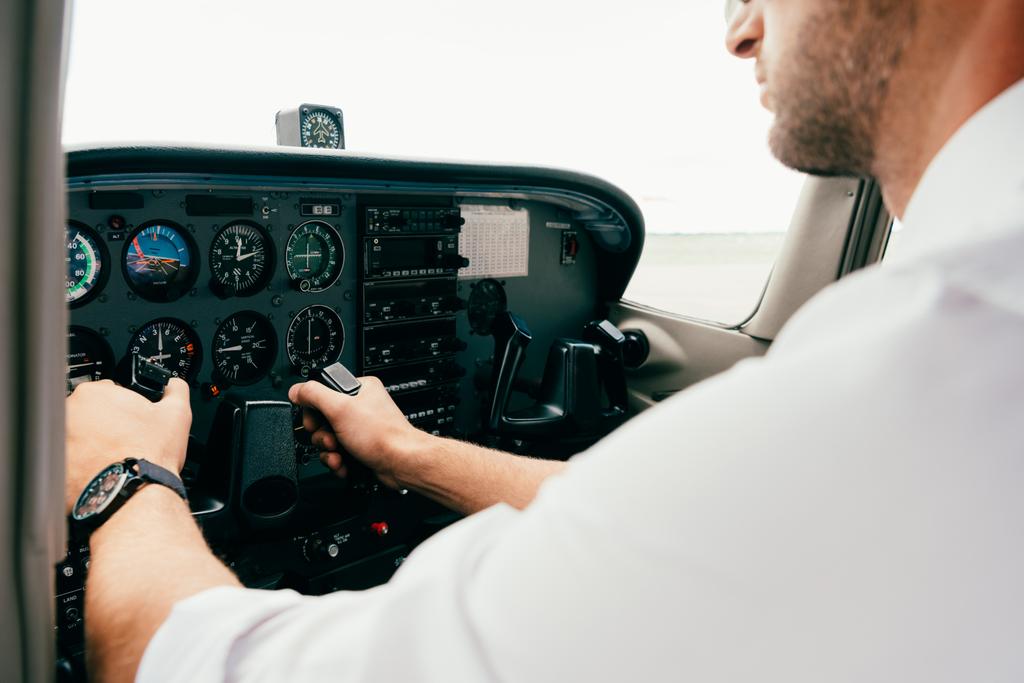 Teilansicht des Piloten in Armbanduhr, der das Steuer im Flugzeug hält - Foto, Bild