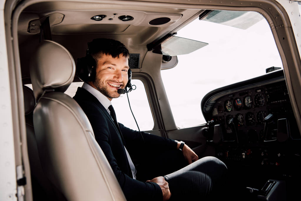 χαμογελαστός πιλότος σε επίσημο ντύσιμο καθισμένος σε αεροπλάνο - Φωτογραφία, εικόνα