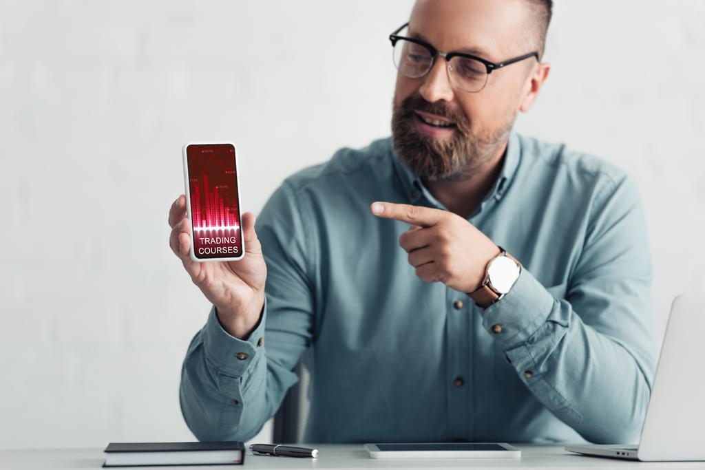όμορφος επιχειρηματίας σε πουκάμισο δείχνοντας με το δάχτυλο στο smartphone με τα μαθήματα διαπραγμάτευσης ιστοσελίδα  - Φωτογραφία, εικόνα