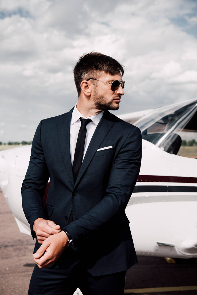 hombre de negocios pensativo en ropa formal de pie cerca de avión en el día soleado
 - Foto, Imagen
