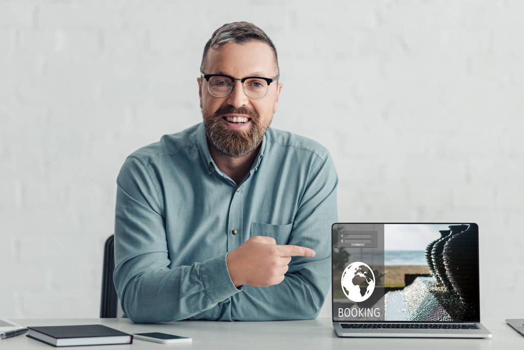 hombre de negocios guapo en camisa que apunta con el dedo a la computadora portátil con el sitio web de reserva
  - Foto, Imagen