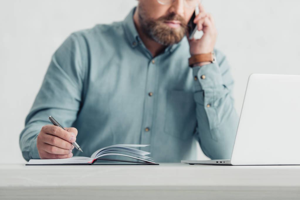 обрезанный вид бизнесмена в рубашке разговаривающего на смартфоне и держащего ручку
 - Фото, изображение