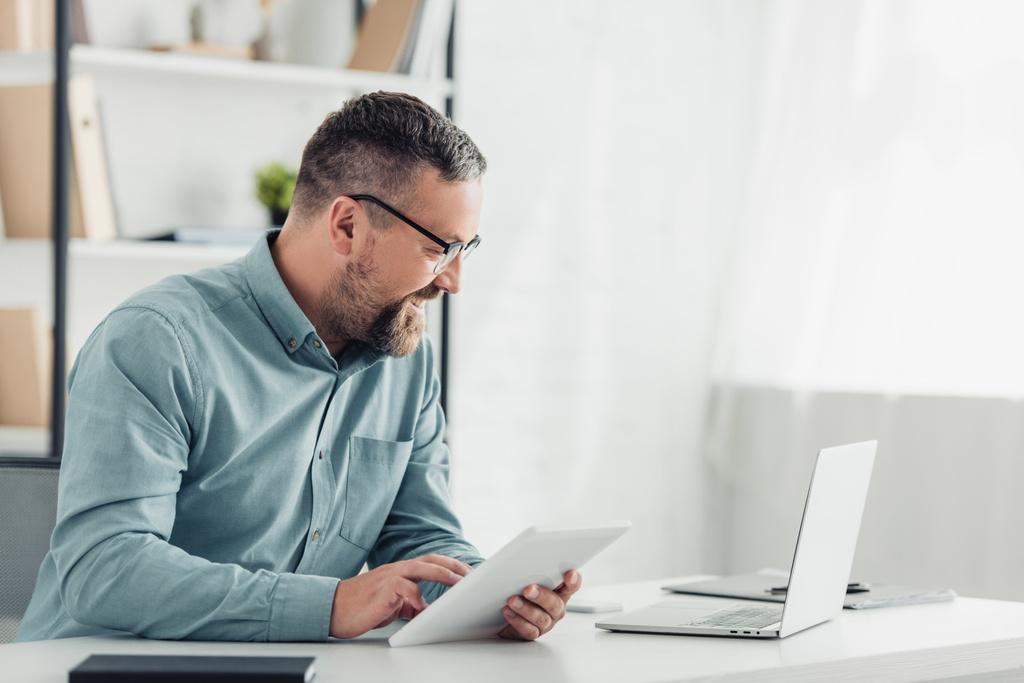 pohledný podnikatel v košili a brýle pomocí digitálního tabletu v kanceláři  - Fotografie, Obrázek