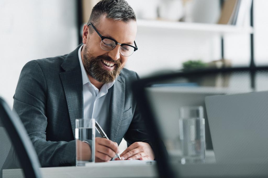 красивий бізнесмен у формальному одязі та окулярах, що пишуть ручкою в офісі
  - Фото, зображення