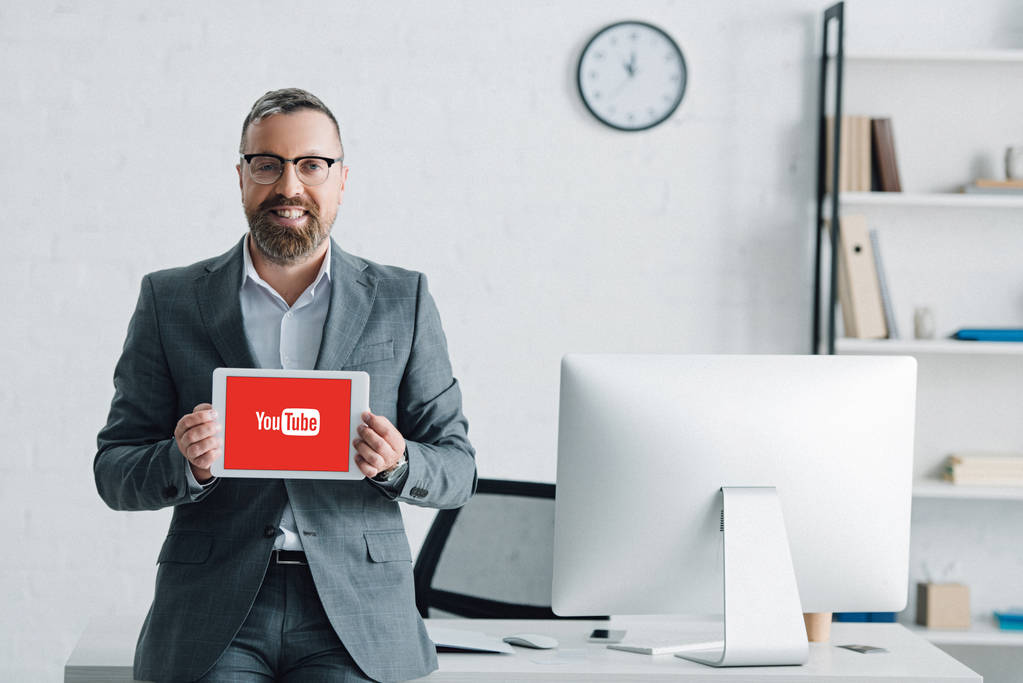 Κίεβο, Ουκρανία-27 Αυγούστου 2019: όμορφος επιχειρηματίας σε επίσημη ένδυση κρατώντας ψηφιακό δισκίο με το λογότυπο του YouTube - Φωτογραφία, εικόνα