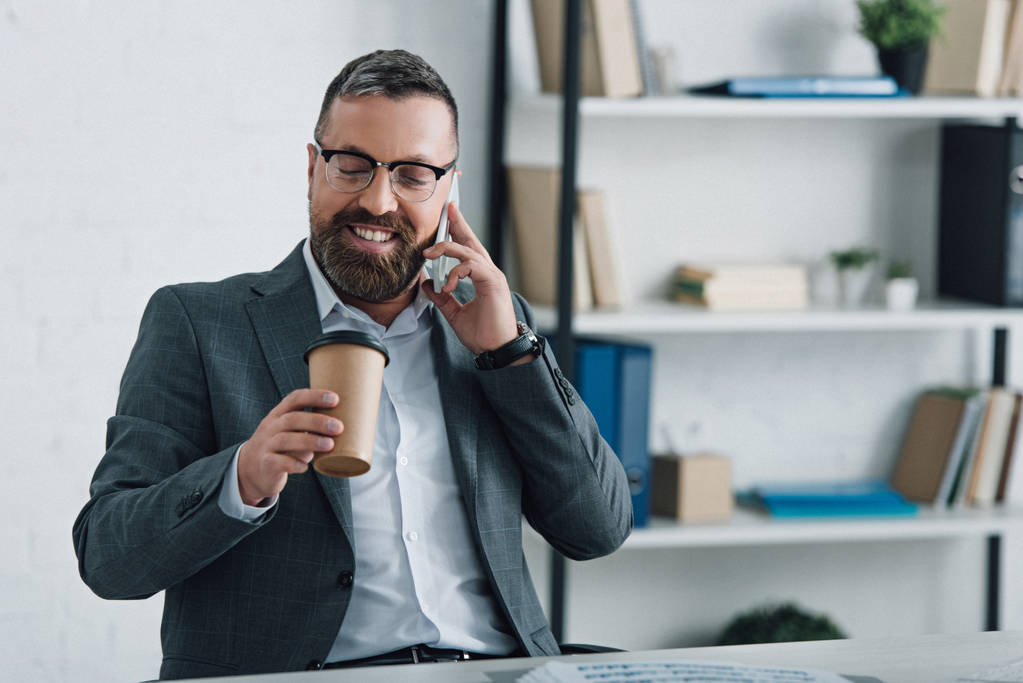 bel homme d'affaires en tenue formelle parlant sur smartphone et tenant tasse en papier
 - Photo, image