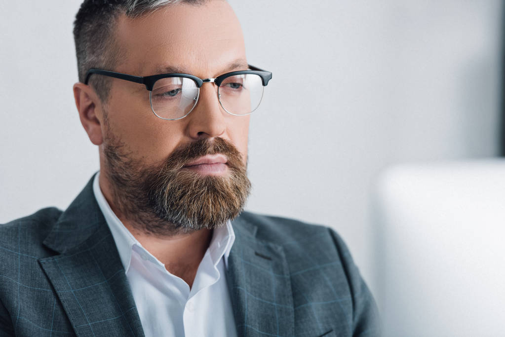 Selektiver Fokus eines gutaussehenden Geschäftsmannes in formeller Kleidung und Brille, der wegschaut  - Foto, Bild