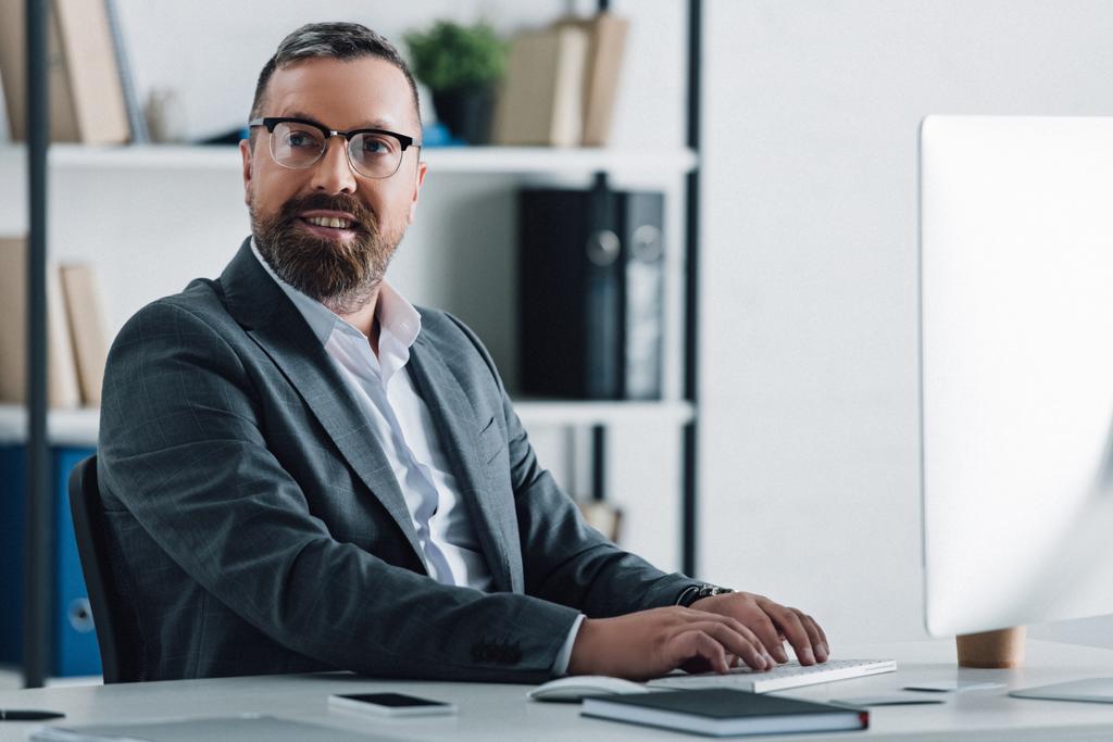 hombre de negocios guapo en ropa formal y gafas usando la computadora
  - Foto, Imagen
