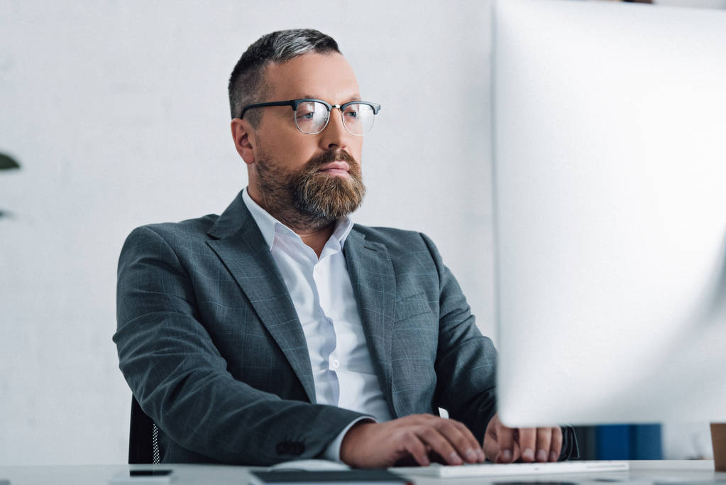 hombre de negocios guapo en ropa formal y gafas usando la computadora
  - Foto, imagen
