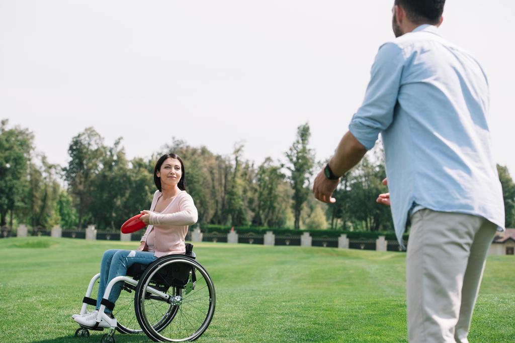 joven mujer discapacitada lanzando disco volador a novio en parque
 - Foto, imagen