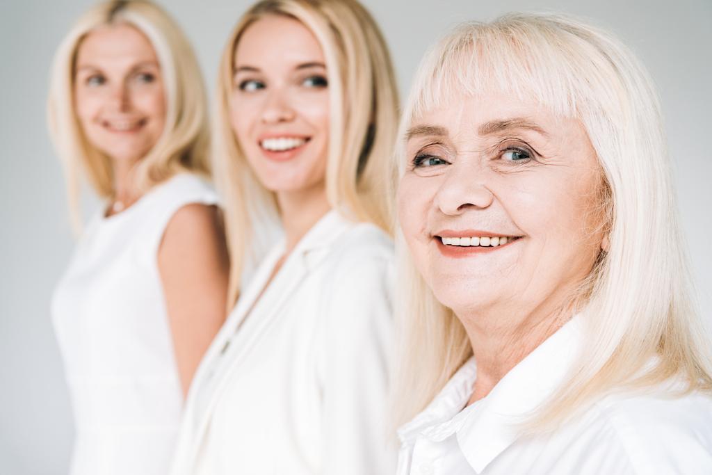 selective focus of three generation blonde women isolated on grey - Photo, Image