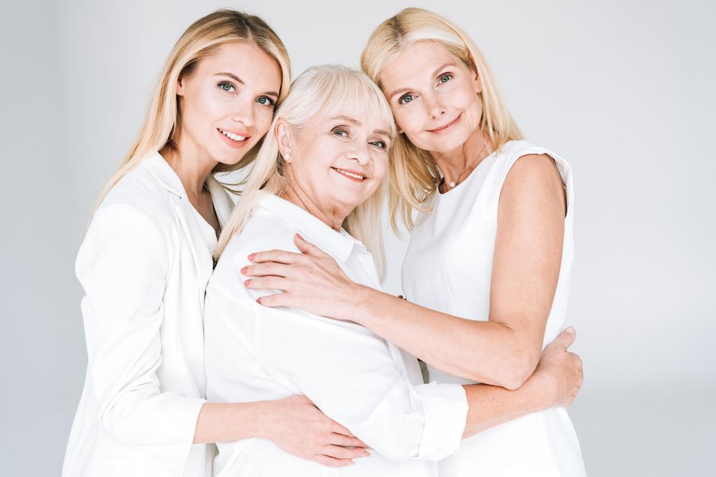 Blonde Frauen der dritten Generation umarmen sich vereinzelt in grau - Foto, Bild