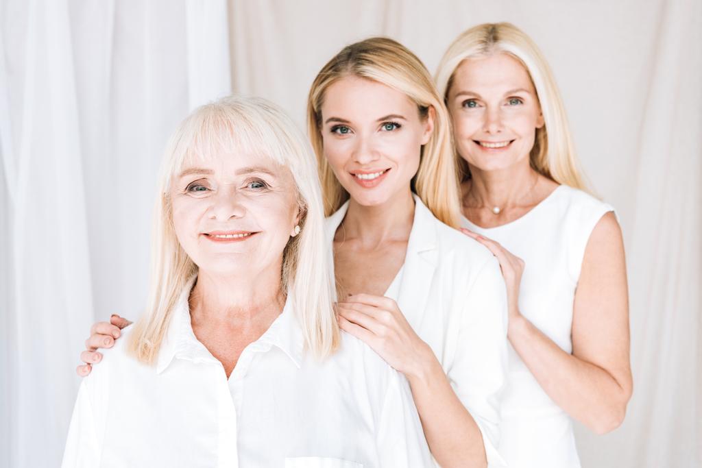 счастливые элегантные блондинки в трех поколениях в белых нарядах
 - Фото, изображение