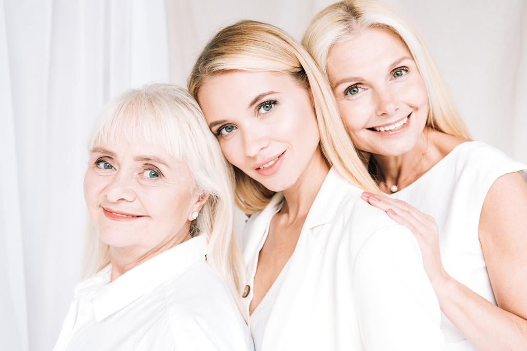 femmes blondes élégantes souriantes de trois générations en tenues blanches totales
 - Photo, image