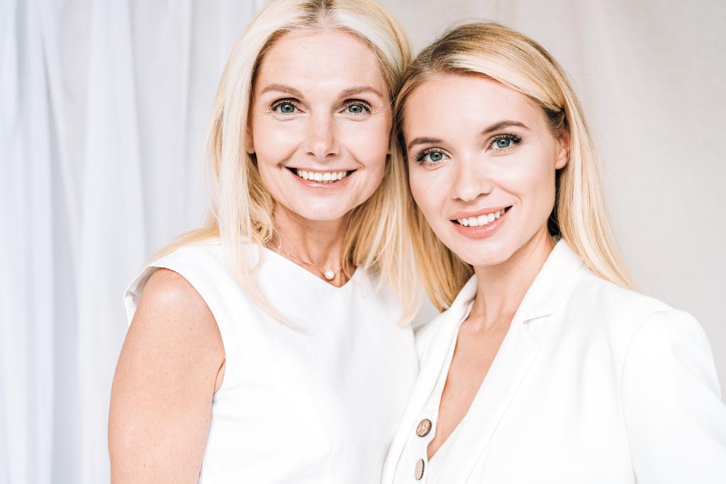 mosolygós szőke anya és lánya a teljes fehér ruhák - Fotó, kép
