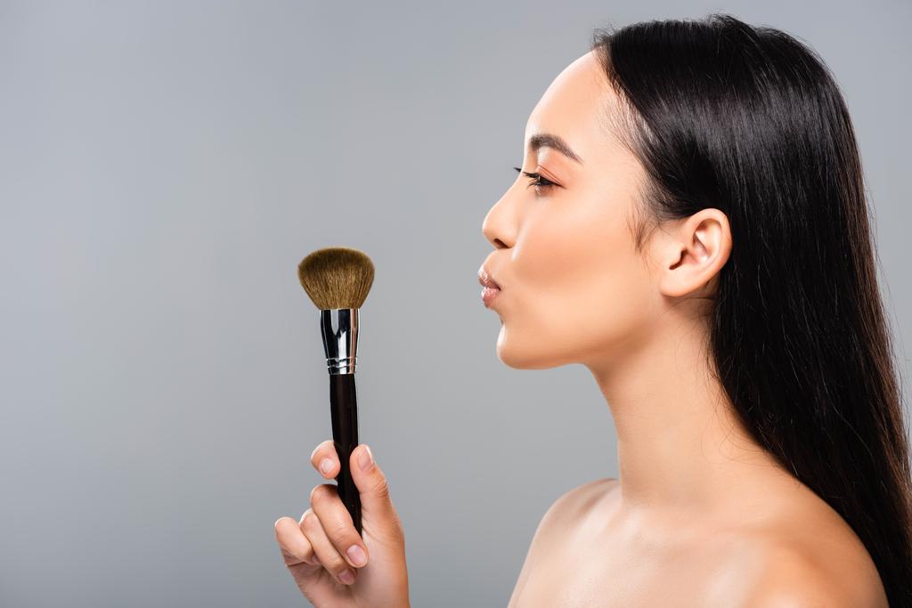side view of beautiful naked asian woman with cosmetic brush isolated on grey - Photo, Image
