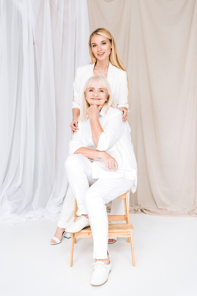 vue pleine longueur de la grand-mère blonde élégante et petite-fille ensemble dans des tenues blanches totales
 - Photo, image