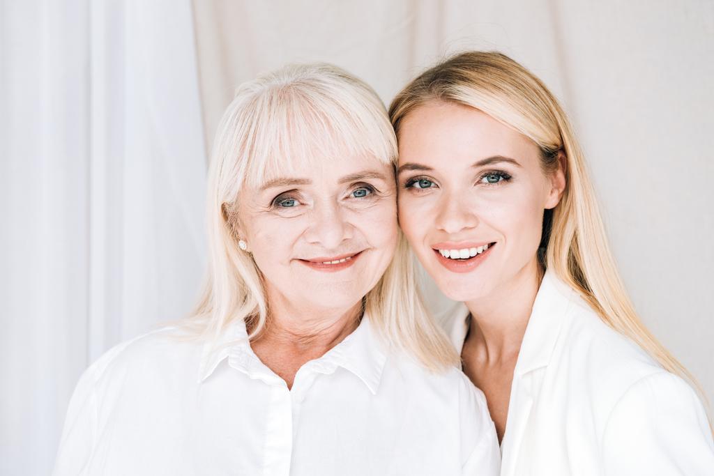 cheerful blonde grandmother and granddaughter together in total white outfits - Photo, Image