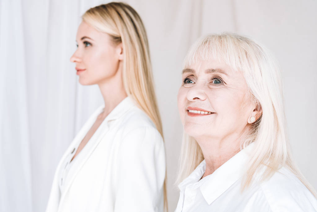 selective focus of blonde grandmother and granddaughter together in total white outfits - Photo, Image