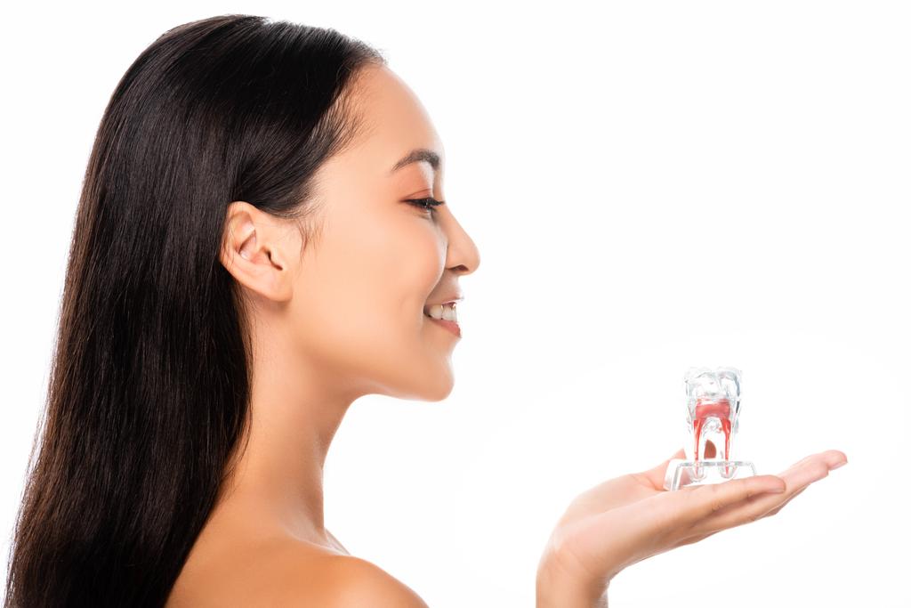 Seitenansicht der glücklichen nackten asiatischen Frau hält Zahn Modell isoliert auf weiß - Foto, Bild
