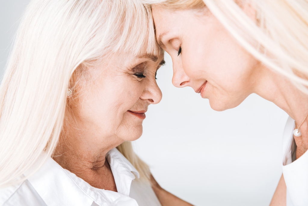 blonde mature fille et mère aînée debout face à face avec les yeux fermés isolé sur gris
 - Photo, image