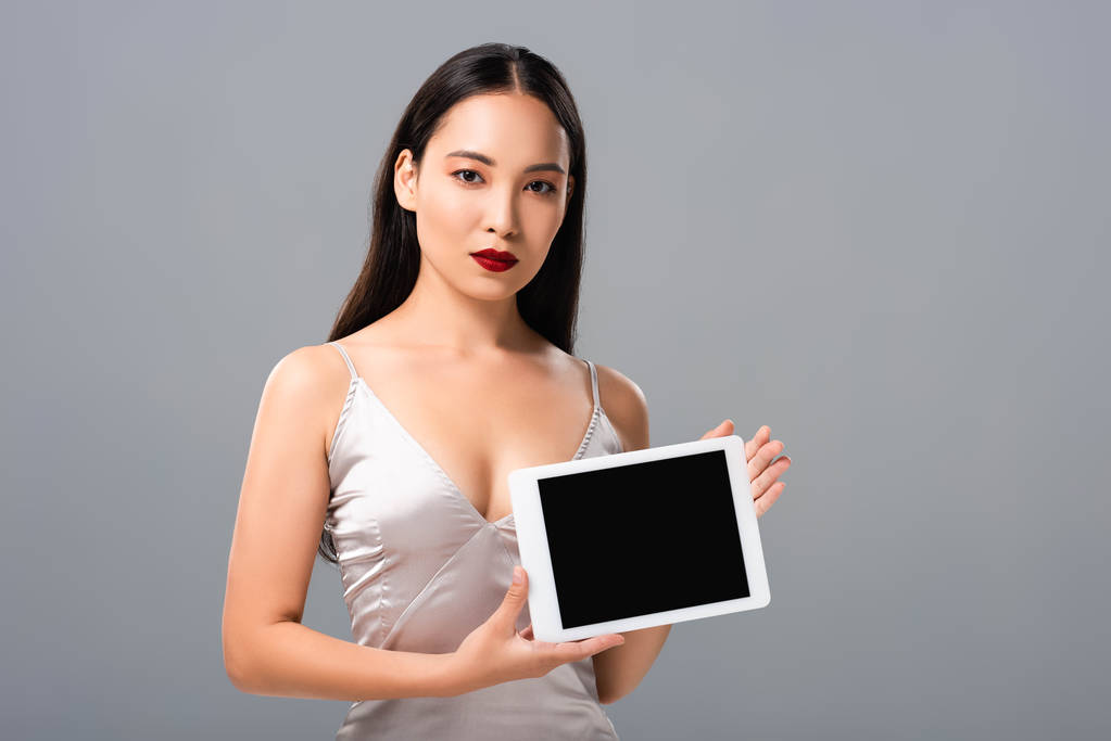 belle femme asiatique en robe de satin avec lèvres rouges tenant tablette numérique avec écran vide isolé sur gris
 - Photo, image