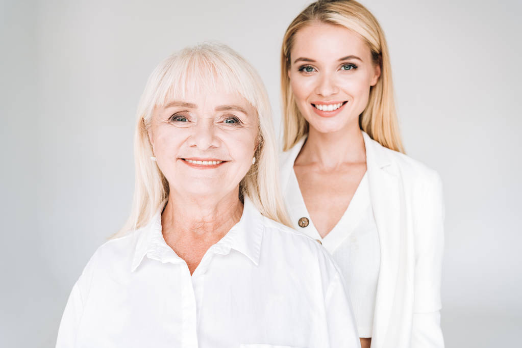 sorrindo loira avó e neta juntos em roupas brancas totais isolados em cinza
 - Foto, Imagem