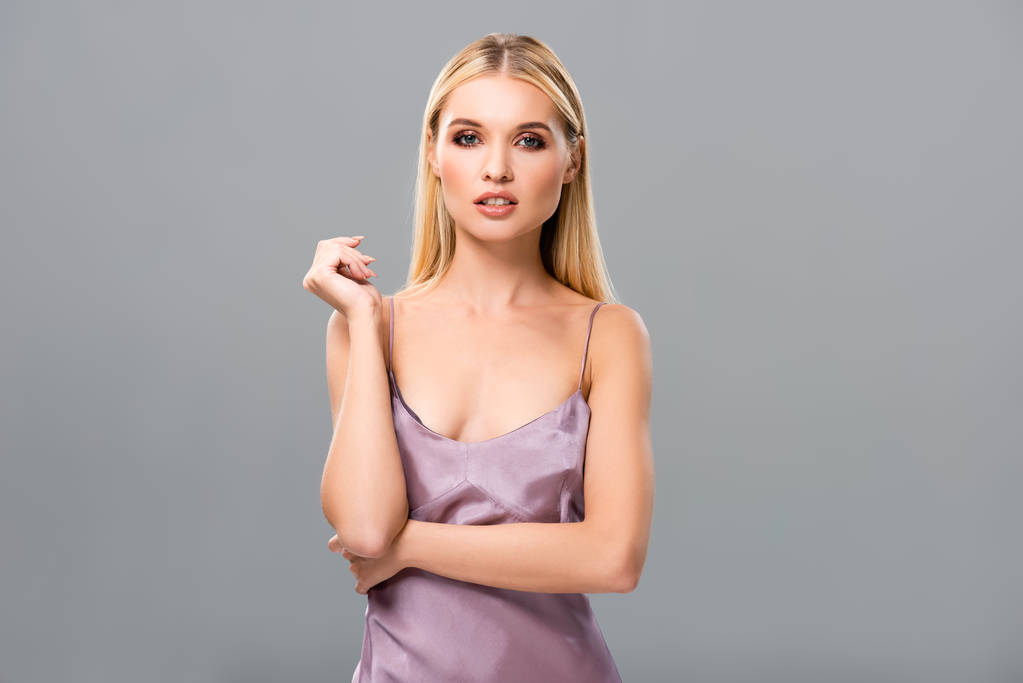 selbstbewusstes, elegantes blondes Mädchen in violettem Satinkleid isoliert auf grau - Foto, Bild