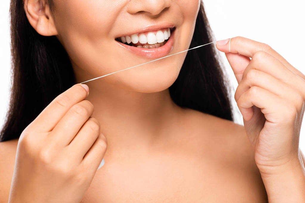 обрізаний вид усміхненої гола жінка з зубною ниткою ізольовані на білому
 - Фото, зображення