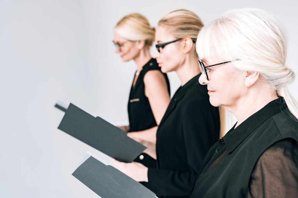 donne d'affari alla moda di tre generazioni in occhiali che tengono cartelle isolate su grigio
 - Foto, immagini
