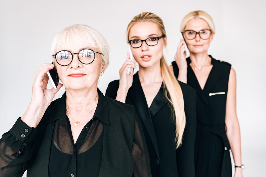 модні бізнесмени трьох поколінь розмовляють на смартфонах ізольовані на сірому
 - Фото, зображення