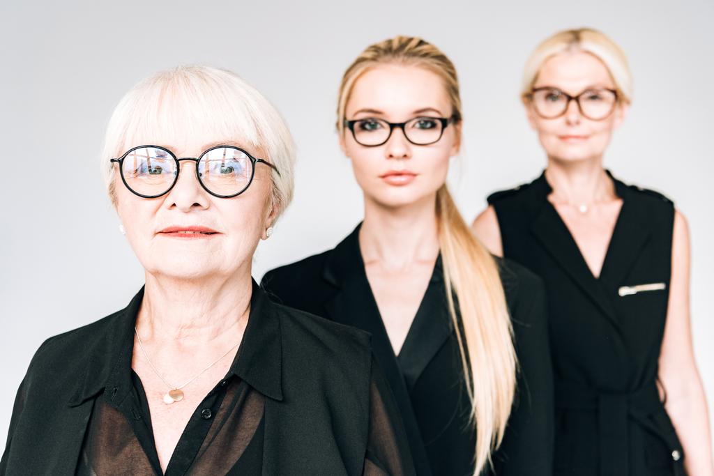 femmes d'affaires blondes à la mode de trois générations dans des lunettes isolées sur gris
 - Photo, image