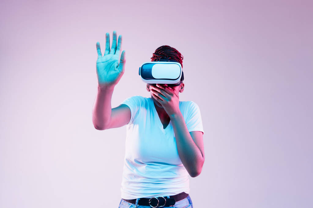Nuori afrikkalais-amerikkalainen naiset käyttävät VR-lasit neon valossa
 - Valokuva, kuva