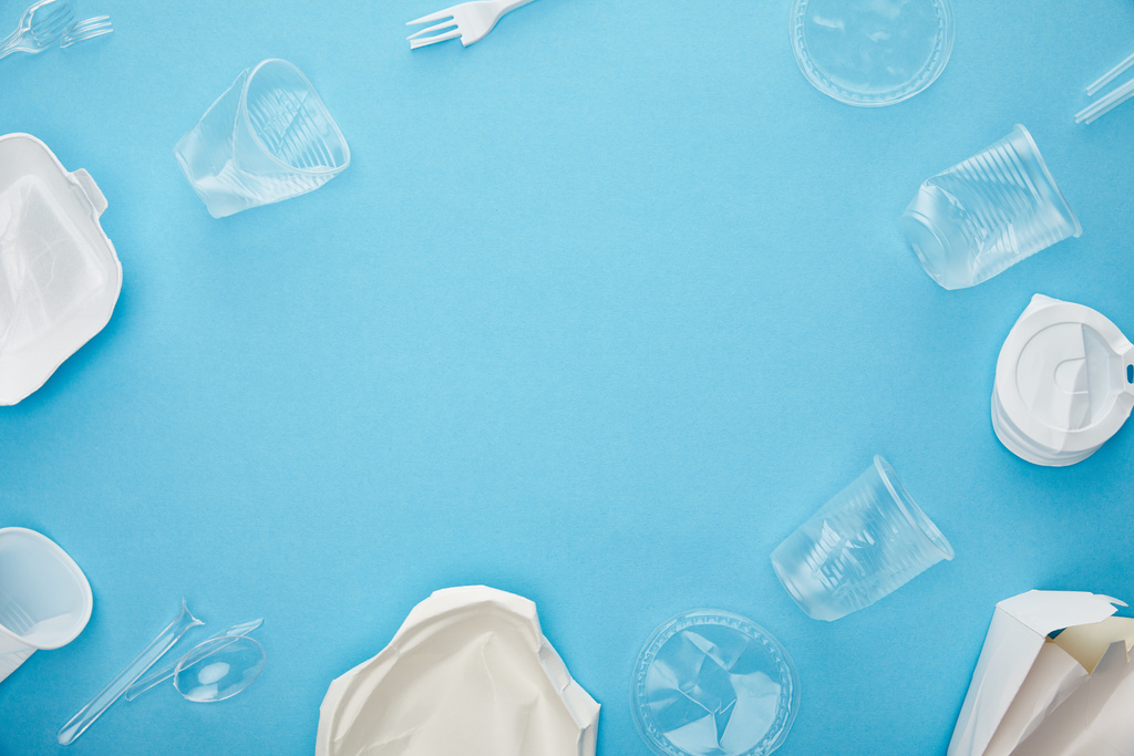 Κορυφαία όψη των πλαστικών κυπελλών μίας χρήσης, πιρούνια, κουτάλια και δοχεία σε μπλε φόντο με χώρο αντιγραφής - Φωτογραφία, εικόνα