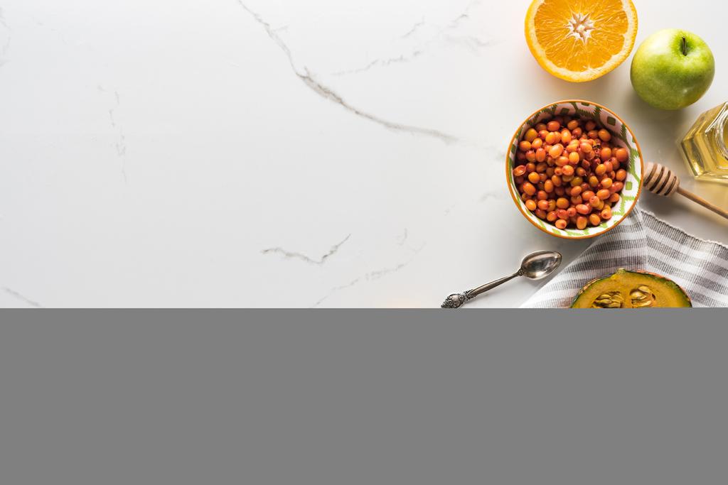 vista dall'alto di asciugamano a strisce con zucca, albicocche, mela e arancia vicino ciotola con olivello spinoso sulla superficie di marmo
 - Foto, immagini
