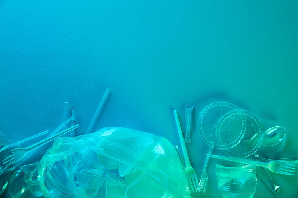 top view of crumpled plastic bags, cups and cardboard rubbish with copy space in blue light - Photo, Image
