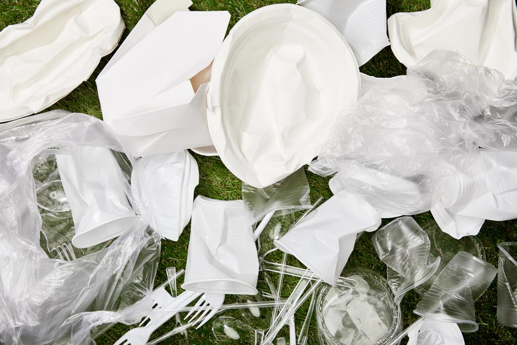 pohled na zmačkané plastové sáčky, šálky a lepenkové odpadky na trávu - Fotografie, Obrázek