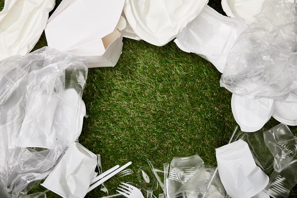 top view of crumpled plastic bags, cups and cardboard rubbish on grass with copy space - Photo, Image