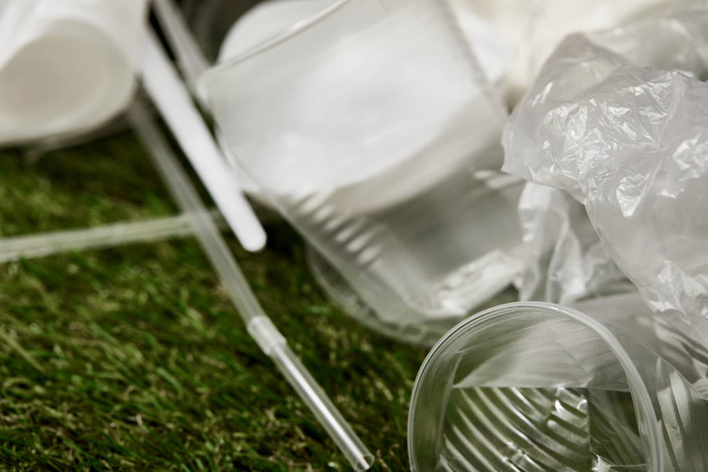 Close-up weergave van verfrommeld plastic bekers en tassen op gras - Foto, afbeelding