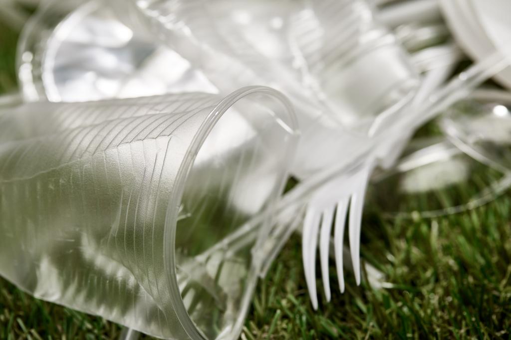 Close-up weergave van verfrommeld plastic bekers en vorken op gras - Foto, afbeelding